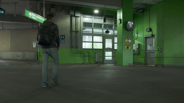 High quality 4k video of a young man walking with the backpack on the empty parking lot. Rush hours to the work. GO station in Canada.