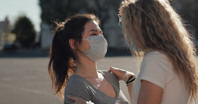 Two multi-racial lesbians kiss through a mask outside in the sun, end of quarantine. LGBT
