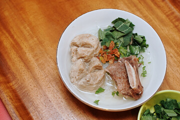 meatball soup with vermicelli and beef ribs. indonesian street food. white bowl. pieces of mustard leaf