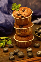 Several fragrant muffins with blueberries are on the table, next to blueberries and mint.