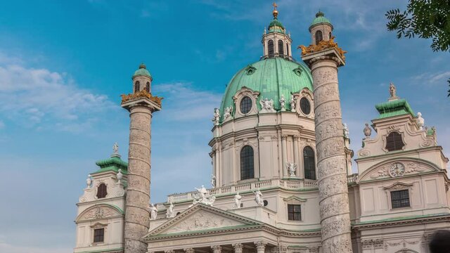 Karlskirche on the Karlsplatz square timelapse in Vienna, Austria. People walking and sitting at fountain. It is a catholic church, also called Rektoratskirche, with a typical baroque architecture.