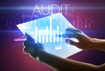 Hand holding futuristic tablet with AUDIT inscription above, modern business concept