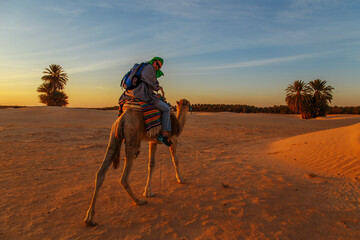 Woman  riding a camel in the Sahara desert.