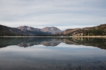 mountains reflecting in still June Lake on a cloudy morning 