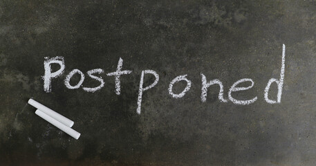 Postponed Word Written on Blackboard with White Chalk