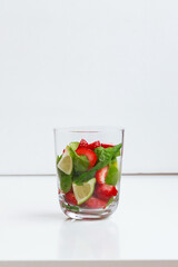 Drink of lime, mint and strawberry in a glass on the table