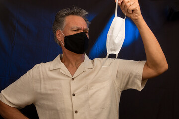 Senior man trying to decided what protective mask to wear the black one or white one 