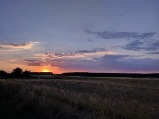 Obraz premium beautiful romantic orange sunset over the empty field with clouds in countryside