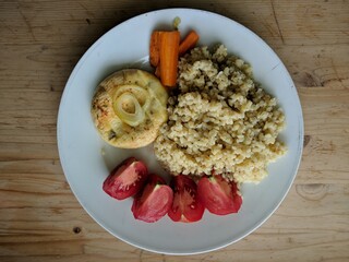 white plate of fresh healthy vegetable food with tomatoes carrot on the wooden table from above