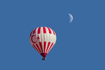 hot air balloon flying high below the moon in turkey 