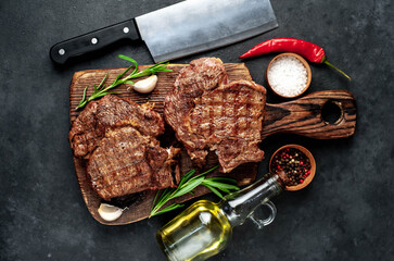Two grilled beef steaks with spices on a stone background