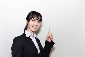 スーツ姿で指を差す若い女性