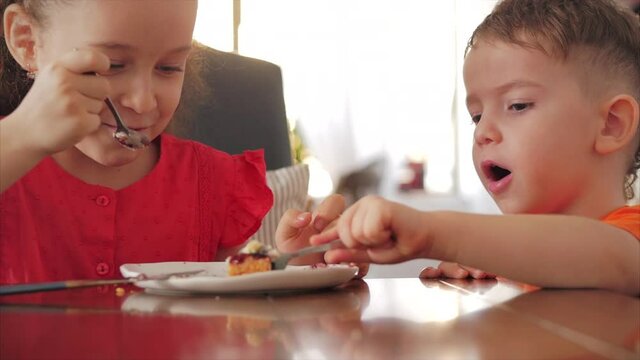 Pretty happy kids eating cheesecake. Sister and brother eat distillation who is faster pudding cake.
