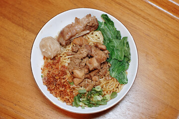 Chicken noodles with some beef meatballs. pieces of mustard leaf. rib meat