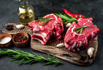 Two raw beef steaks with spices on a stone background.