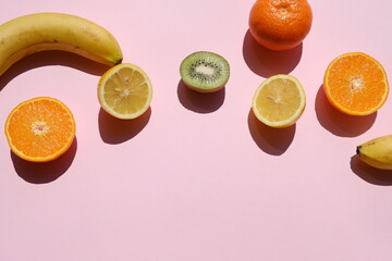 Various tropical fruits on a pink background, top view