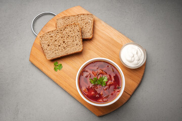 Vegetarian borscht in a disposable dish for delivery near sour cream and bread on a wooden Board top view