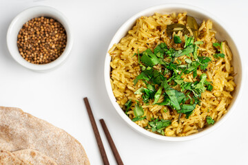 Kichari in a white plate on a light table near condiments and tortillas top view