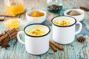 Detox drink. Golden milk with turmeric and cinnamon in mugs on a wooden table. Rustic style