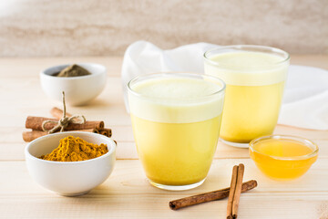Detox drink. Golden milk with turmeric and cinnamon in glasses on a wooden table.