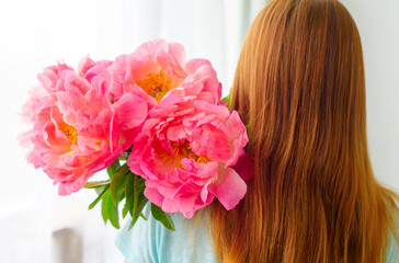 red-haired girl with a bouquet of pink peonies for her mother or grandmother