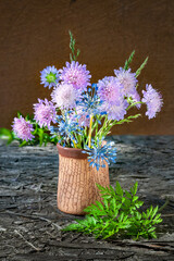 Bouquet of clover and garlic flowers in a vase. Rustic still life with clover wildflowers. Selective soft focus.