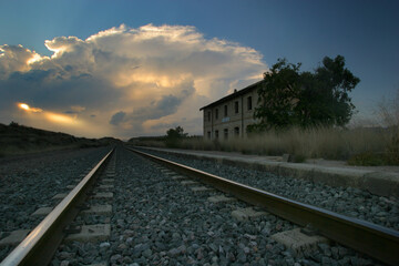 Fototapeta na wymiar Vía del ferrocarril en estación abandonada, con tormenta al fondo.