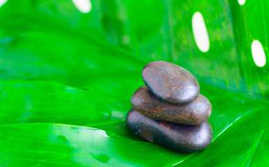Obraz na płótnie Canvas pyramid of stones on monstera leaf. balanced zen stones. spa and relax concept.