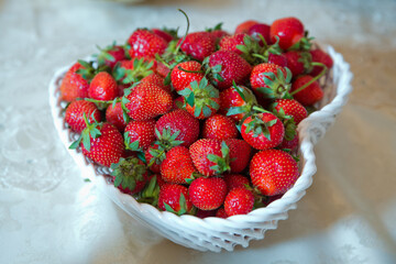 Sweet strawberries in the little basket. Symbol of love. Heart shape bowl, summer juicy strawberries . Strawberry white heart in a basket bowl .
