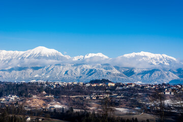 Radovljica town in Slovenia on sunny winter day. Snow covering parts of landscape and completely Alps mountains. Beautiful nature in wintertime