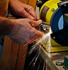 Picture of worker's hands sharpening rod with sparks.