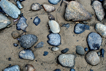 Sea stones of various shapes in the sand.