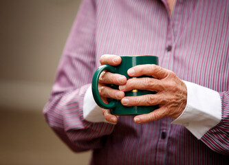 Hands of elderly woman with arthritis holding cup