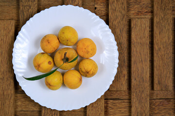 Fresh ripe tasty eggfruits in a white bowl isolated on wooden background