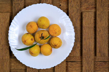 Fresh ripe tasty eggfruits in a white bowl isolated on wooden background