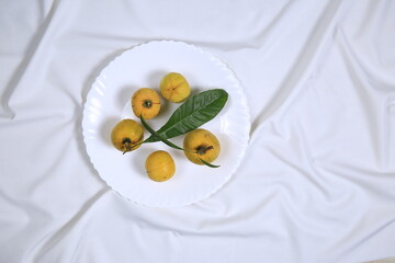 Fresh tasty eggfruit with leaves on a white bowl
