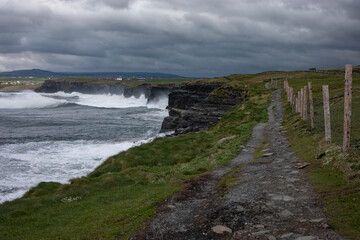 Landscape of coastal cliff walk on a stormy, cloudy day with rough sea in Doolin, Co. Clare, Ireland. Wild Atlantic Way.