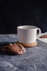 White cup of coffee and chocolate cookie on black stone background. Sweet, copy. Homemade cookies with chocolate.