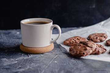 White cup of coffee and chocolate cookie on black stone background. Sweet, copy. Homemade cookies with chocolate.