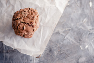 An overhead closeup photo of chocolate chips cookies, shot from above on a piece of baking paper on dark grey background, with copy space.