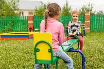 Two little girls have fun on a swing outdoors
