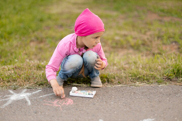 The child drawing a chalk on asphalt. Child drawings paintings on asphalt concept.