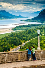 Columbia River Gorge, Oregon - two young women tourists standing at a rock wall at crown point