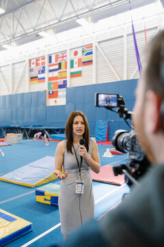 News Reporter Using Microphone In Gymnasium