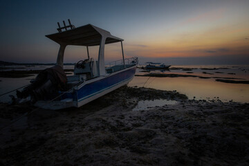 Fototapeta na wymiar Two boats stranded on sand at dusk, Nusa Lembongan, Bali