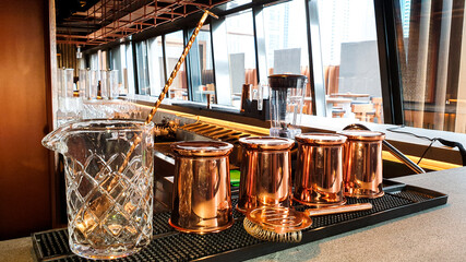 Moscow mule copper mugs on a bar counter. A Moscow mule is a cocktail made with vodka, spicy ginger beer, and lime juice, garnished with a slice or wedge of lime