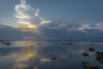 Sunset over a partly sunny sky reflecting on the sea