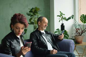 Family portrait of adult daughter and senior father in loft room with houseplants. Man and girl are...