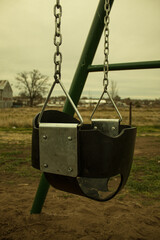 
Brightly colored metal swing tied with chains on a cloudy day
