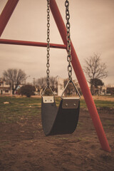 
Brightly colored metal swing tied with chains on a cloudy day